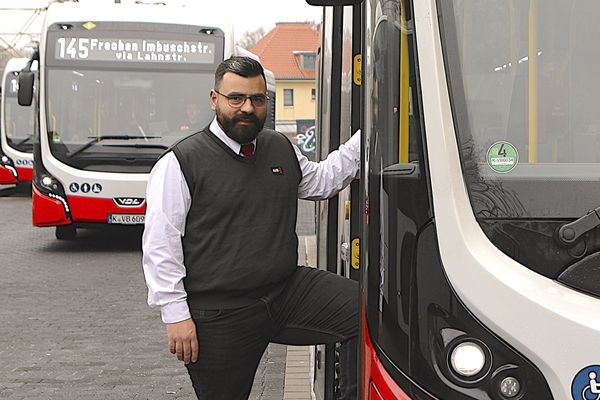 Foto: Ein Busfahrer steht mit einem Fuß in der Tür eines Busses