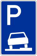 Das Bild zeigt ein Verkehrsschild, das Gehwegparken erlaubt. Auf blauem Hintergrund ist ein weißes Piktogramm eines Autos abgebildet, das aufgesetzt auf einem Bürgersteig parkt. Darüber ein großes "P".